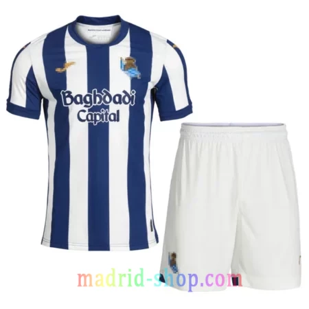 Camiseta Real Sociedad Primera Equipación 2026-27 Niño conjunto infantil con pantalón corto blanco.